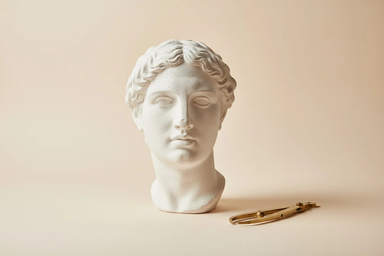 A plaster study head beside a pair of callipers — the proportion canon predates any camera